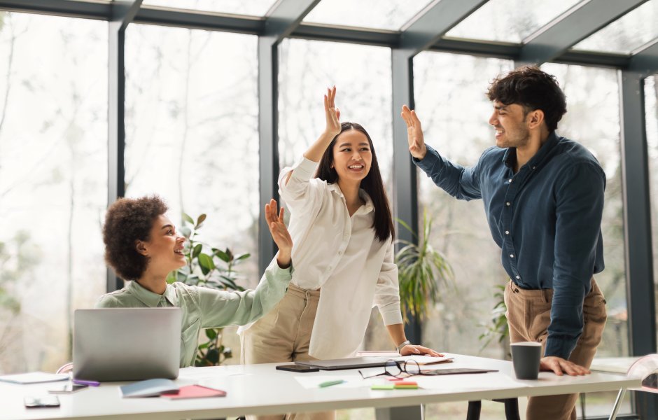 Três colegas de trabalho sorridentes celebram com um 