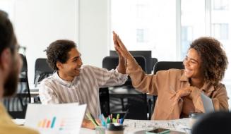 Dois colegas de trabalho sorridentes celebram com um 