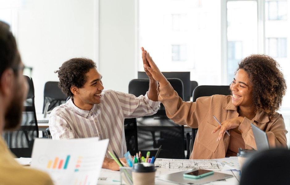 Dois colegas de trabalho sorridentes celebram com um 