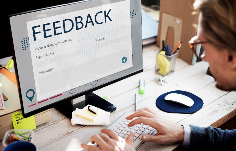 Pessoa diante de um monitor exibindo um formulário de feedback com campos de e-mail, usuário e mensagem.