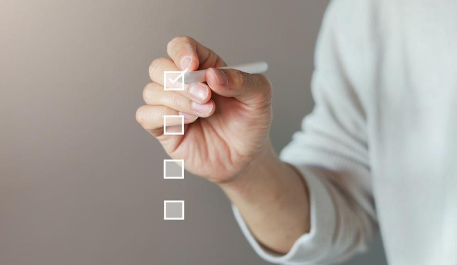 Pessoa marcando opções em uma lista de verificação com caneta, simbolizando planejamento ou tomada de decisão.