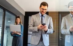 Homens e mulher de negócios usando smartphones e laptop em ambiente de escritório moderno, profissionais conectados e comunicativos.