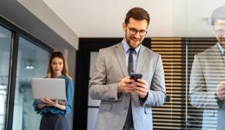 Homens e mulher de negócios usando smartphones e laptop em ambiente de escritório moderno, profissionais conectados e comunicativos.