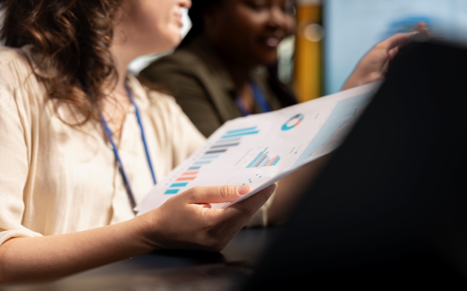 Profissionais analisando relatório com gráficos em reunião de trabalho