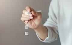 Mão marcando o primeiro item de uma checklist virtual, simbolizando tarefas ou avaliação.
