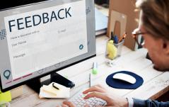 Pessoa diante de um monitor exibindo um formulário de feedback com campos de e-mail, usuário e mensagem.