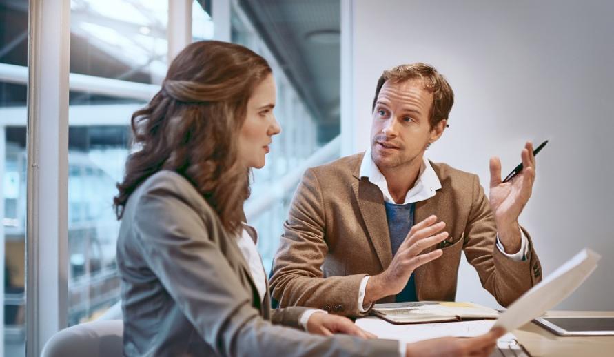 Reunião de negócios entre um homem e uma mulher em um escritório, discutindo estratégias e ideias para crescimento empresarial.