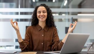 Mulher relaxada fazendo meditação no ambiente de trabalho, praticando mindfulness e encontrando equilíbrio no escritório.