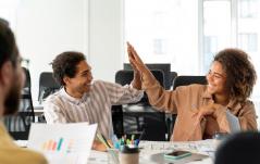 Dois colegas de trabalho sorridentes celebram com um 
