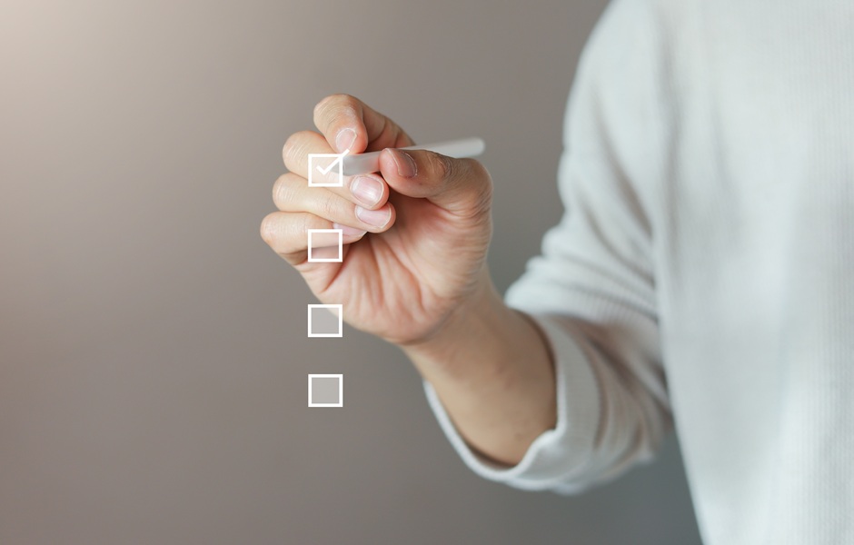 Pessoa marcando opções em uma lista de verificação com caneta, simbolizando planejamento ou tomada de decisão.