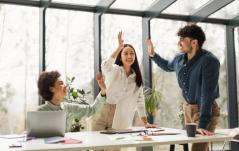 Três colegas de trabalho sorridentes celebram com um 