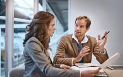 Reunião de negócios entre um homem e uma mulher em um escritório, discutindo estratégias e ideias para crescimento empresarial.