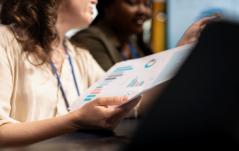 Profissionais analisando relatório com gráficos em reunião de trabalho
